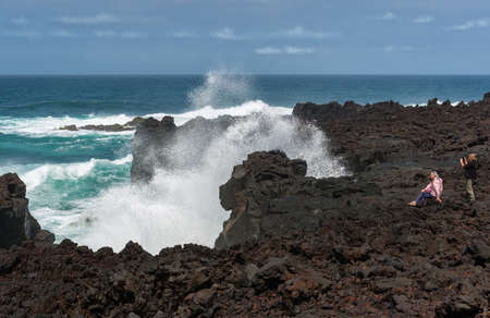 PONTA DEL GADA, SAN MIGUEL, AZORES-APRIL 26, 2016: tourists taking pictures on a rough black rocky cliffのeditorial素材