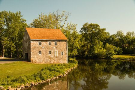 Old stone house next to a tree-lined winding stream in eastern Pennsylvania on a summer dayの写真素材