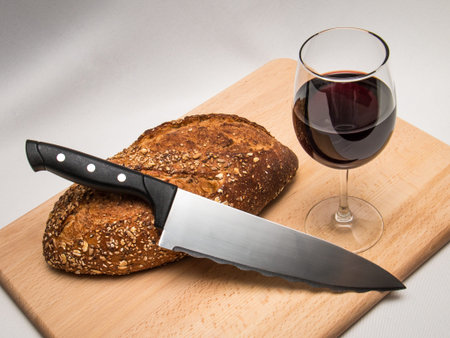 Traditional Christian Communion elements of bread and wine on a cutting board with a knife