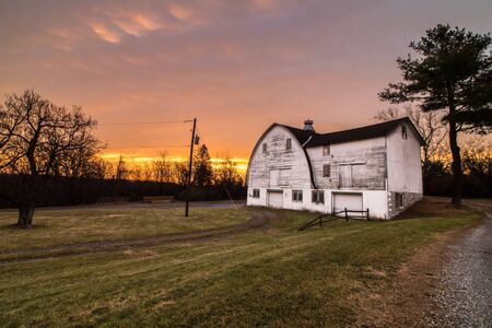 Dawn breaks out some beautiful colors over a field with a white barn in Blue Marsh State Park in Berks County, PAの写真素材