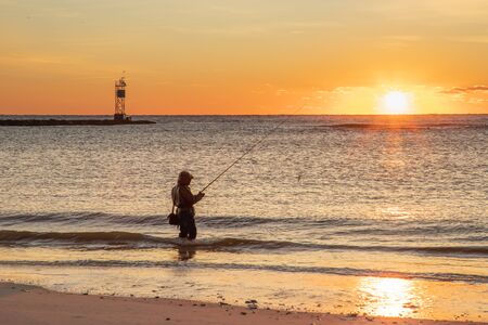 Sunrise greets a single surf fisherman next to the entrance to Barnegat Inletの写真素材