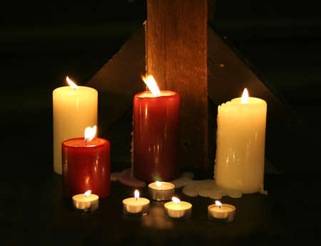 Candles set against a rough wood beam in the darknessの写真素材