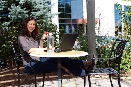 Woman relaxing as she works outside the officeの写真素材