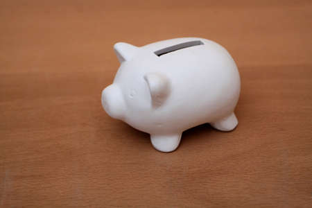 A white piggy bank on a wooden tableの写真素材