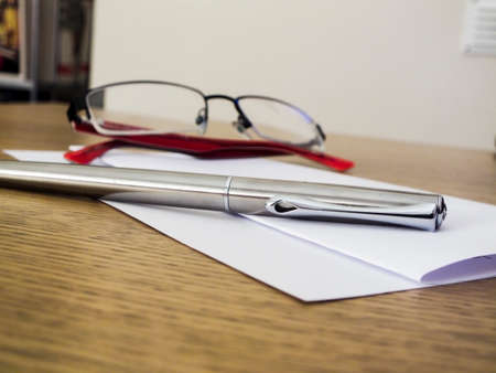 A hand written letter with a pen and glasses on top の写真素材
