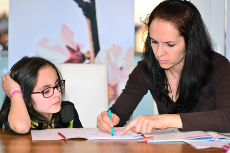 Mother helping little girl to do homeworkの写真素材