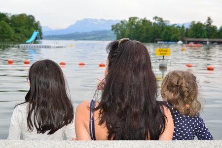 Mother and her girls contemplating a lake in a summer eveningの写真素材