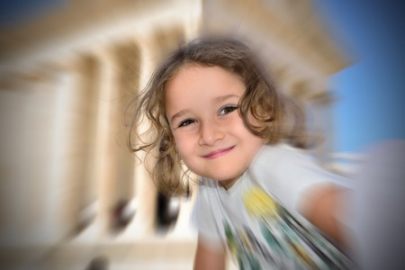 Little cute girl posing in front of a good preserved roman templeの写真素材