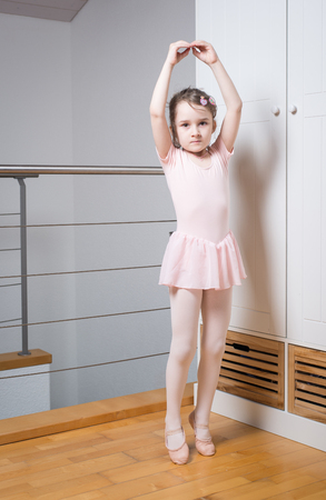 Little girl wearing a ballet dress is practicing ballet in a dance studioの写真素材