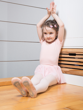 Little girl wearing a ballet dress is practicing ballet in a dance studioの写真素材