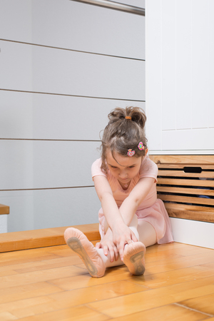 Little girl wearing a ballet dress is practicing ballet in a dance studioの写真素材