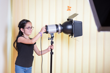 Little cute girl learning the lighting technique in a photostudioの写真素材