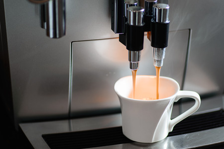 Close up of espresso coffee machine dispensing coffee into a coffee cupの写真素材