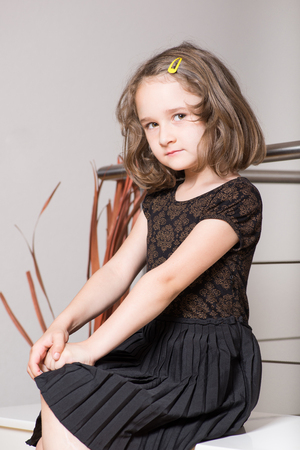 Cute little blonde girl posing on a benchの写真素材