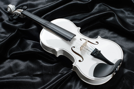 Closeup of a white violin on a background of  black satinの写真素材