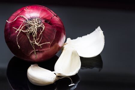 Red onion and garlic with reflection on a black backgroundの写真素材
