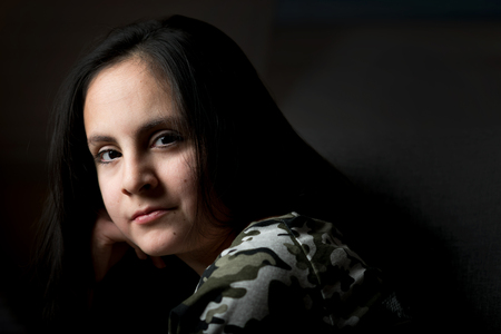 Cute brunette girl with long hair posing in low keyの写真素材