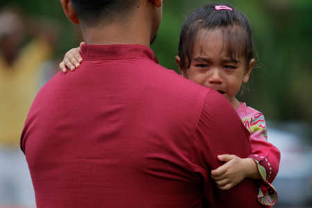 A girl cries as she is hug by her father after she watched a goat slaughtering  during Eid Al-Adha Al Mubarak, the Feast of Sacrifice cerebration which held at  Masjid Muhammadiah, the Chinese Mosque in Ipoh, Perak, Malaysia.のeditorial素材
