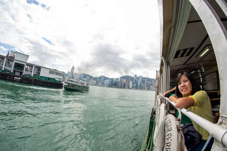 A tourist looks out from a ferry as she takes a tour from Star Ferry Pier to Victoria Harbour in Hong Kongのeditorial素材