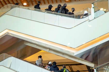 Protesters walk down an escalator above a man carrying his child as they shopping during a protest is held at New Town Plaza of Sha Tin in Hong Kongのeditorial素材