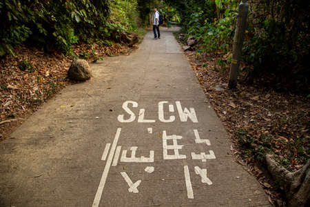 Faded Chinese and English "Slow" sign is seen on the track of Lamma Island, Hong Kongのeditorial素材