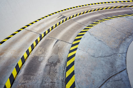 Entry to garage. Empty road to the underground car park with black and yellow safety stripes on...
