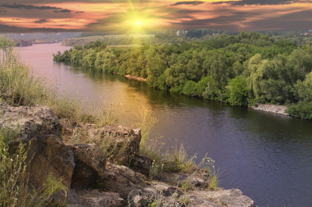 Landscape with rock and river on sunset background.