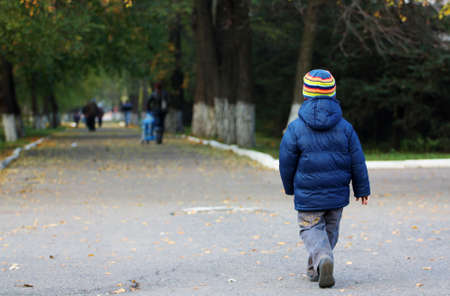 Little boy walking away in the autumn parkの写真素材