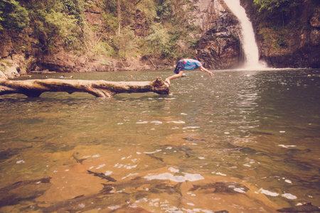 The man is jumping in the water at water fall in thailand.(vintage style)の写真素材