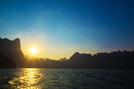 Sunset behind mountain and blue sky at Khaosok Lake, Thailandの写真素材