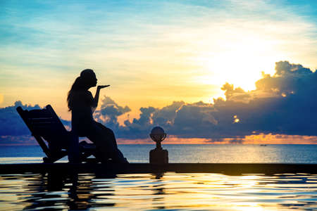 woman sit on at swimming pool in sunset.の写真素材