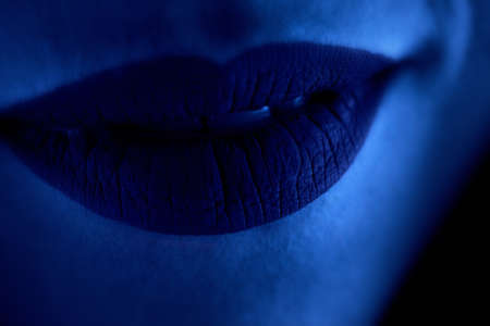 Lips close-up in blue neon lightの写真素材