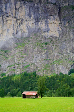 Small Barn close to a Steep Rocky Mountain in Switzerlandの写真素材