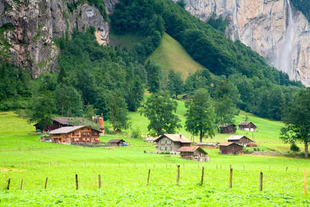 Houses and Barns close to a Steep Rocky Mountain in Switzerlandの写真素材