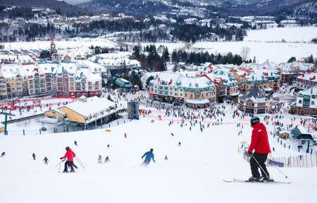 Mont-Tremblant, Canada - February 9, 2014  Skiers and snowboarders are sliding down the main slope at Mont-Tremblant  Mont-Tremblant Ski Resort is acknowledged by most industry experts as being the best ski resort in Eastern North America のeditorial素材