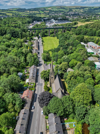 Historic church surrounded by lush greenery and scenic landscape near a small town with a bridge in the distanceの写真素材