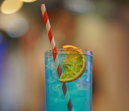 Colorful cocktail served in a tall glass with a slice of lime, set against a blurred background, creating a vibrant atmosphere for relaxationの写真素材