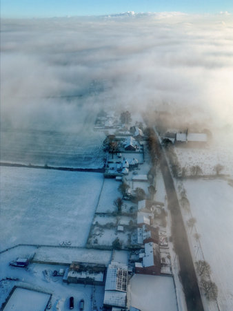 Snow-covered village under a blanket of mist in the early morning lightの写真素材