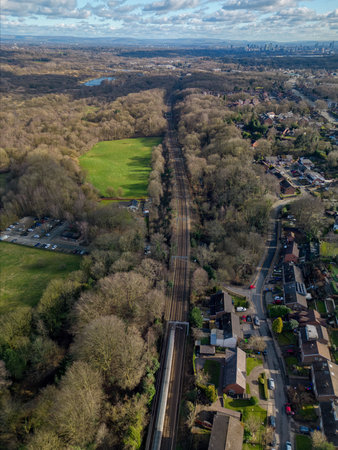 Scenic view of a train passing through trees near a neighborhood and park during daylight hoursの写真素材