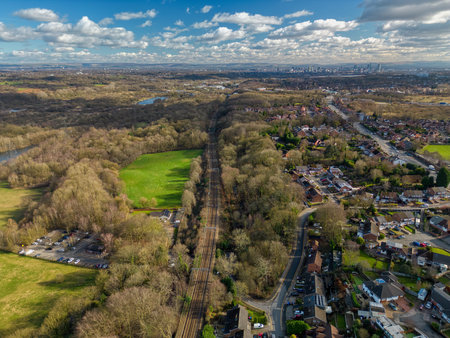 Expansive view of a railway track surrounded by trees and residential areas on a clear dayの写真素材