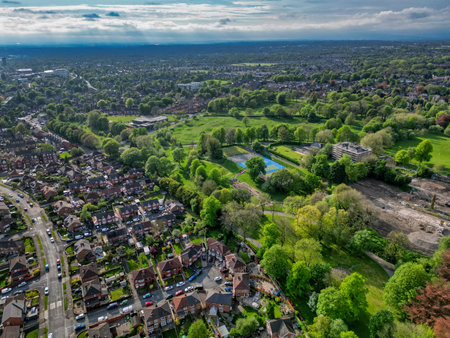 View of a lush green park surrounded by residential areas and urban development in a suburban landscape during daylightの写真素材