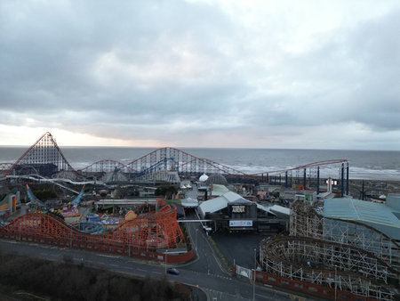 Amusement park with roller coasters and ocean views during a cloudy dayの写真素材