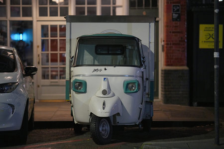 Unique three-wheeled vehicle parked in front of a charming building at night in an urban setting