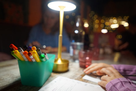 Group of friends enjoying a creative night with markers and drinks at a cozy restaurant in the eveningの写真素材