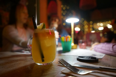 Refreshing cocktail served at a lively night gathering in a cozy bar settingの写真素材