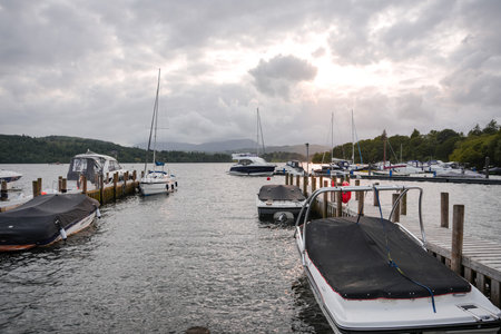 Boats docked at a serene marina during twilight with cloudy skiesの写真素材