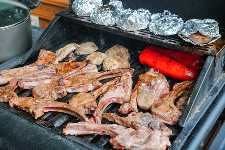 Delicious lamb chops and vegetables grilling on barbecue at a backyard gathering during summerの写真素材