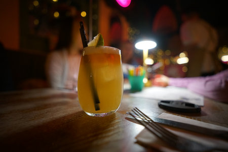 Refreshing tropical cocktail served in a glass with garnishes in a vibrant bar during the eveningの写真素材