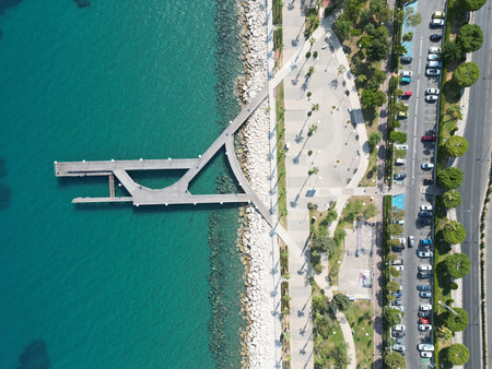 Scenic aerial view of a modern pier extending into turquoise waters near a vibrant coastal promenadeの写真素材