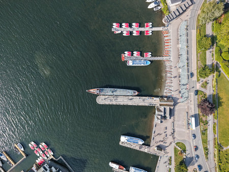 Waterfront marina with boats docked and people enjoying a sunny day by the waters edgeの写真素材